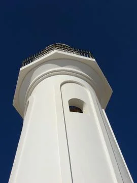 White lighthouse against the blue sky on a sunny day Stock Photos