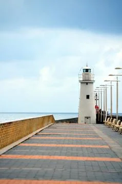 White lighthouse at the bottom of the road Stock Photos
