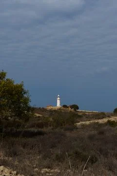 White lighthouse far away in cloudy weather Stock Photos
