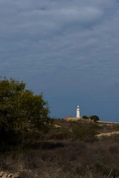 White lighthouse far away in cloudy weather Stock Photos