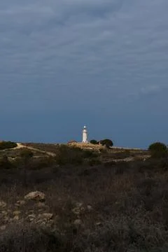 White lighthouse far away in cloudy weather Stock Photos
