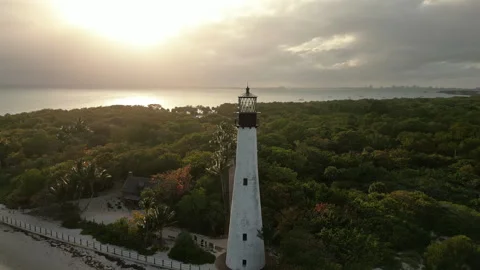 White Lighthouse with Golden Sunset over Ocean Aerial Stock Footage 317435599