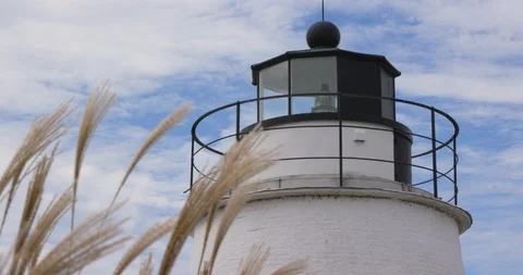 White Lighthouse Lantern Room Along Sea with Swaying Grass Stock Footage 119001390