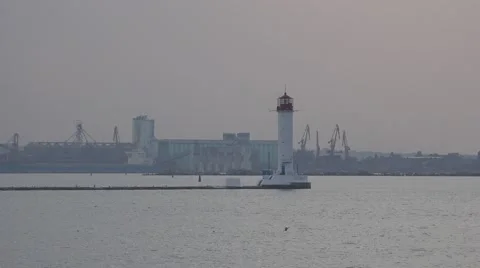 White lighthouse on pier on background of sea port in morning mist Stock Footage