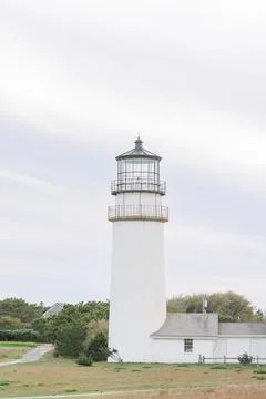 White lighthouse providing guidance on overcast day Stock Photos