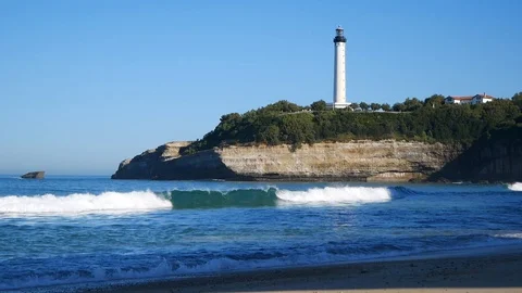 White lighthouse rises on a cliff, view from a sandy beach Video stock 127892758