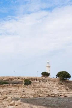 White lighthouse s under a partly cloudy sky flanked by trees Stock Photos