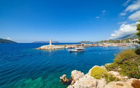 White lighthouse, sightseeing ship in clear blue sea in Kas, Turkey Fotos Stock