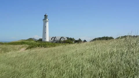 White lighthouse standing on grassy coastal hill Stock-Footage 338329213