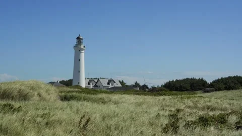 White lighthouse standing on grassy dunes Vídeo Stock 338329173