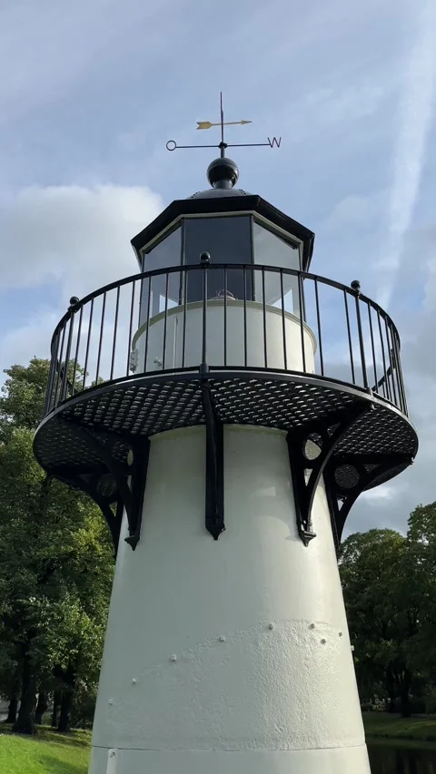 White Lighthouse Tower Against Blue Sky and Green Trees Stock Footage 344004463