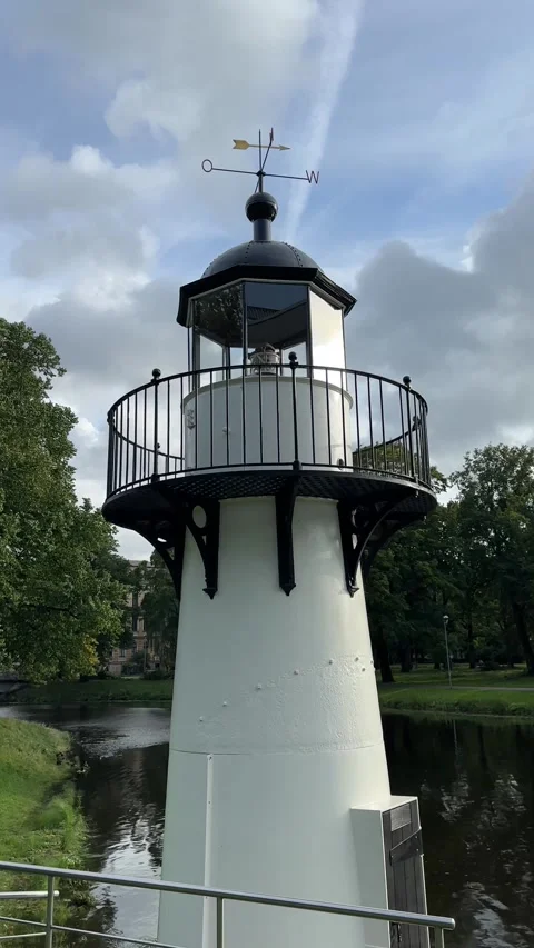 White Lighthouse Tower Against Blue Sky and Green Trees Stock Footage 344004468