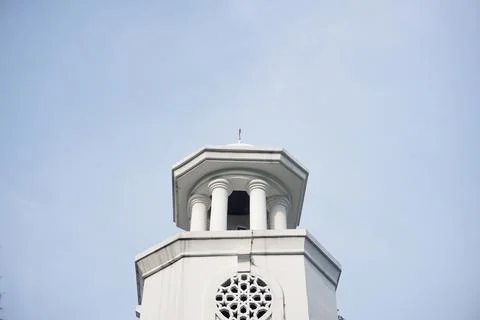 White lighthouse tower with decorative clock and balcony against clear blue s Stock Photos