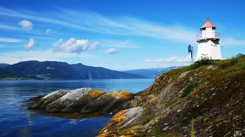 White lighthouse tower with red top and moss covered rocky shore in Norway. Stock Footage 120432584