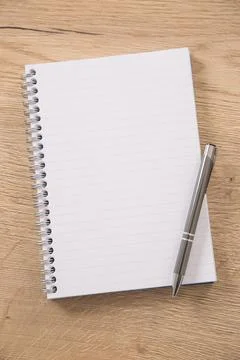 White lined notepad with a metal ring wire binding and a silver pen opened .. Stock Photos