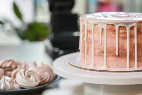 White liquid chocolate flows down to the edges of a beautiful pink cake on a Stock Photos