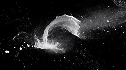 White liquid splash forms broad curling arc across black background, with dense Video stock 338436601