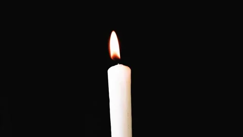 White long candle close-up. The flame of a candle slowly shakes from the air Видео 107780980