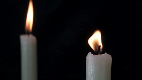 White long candle close-up. The flame of a candle slowly shakes from the air Stockbeeldmateriaal 107781451