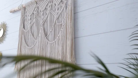 White macrame hanging on a wall through green leaves Stock Footage 120986706