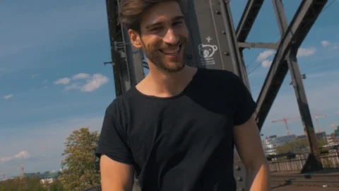 White male model laughing into the camera posing on a bridge signing stop filmin Stock Footage 87260865