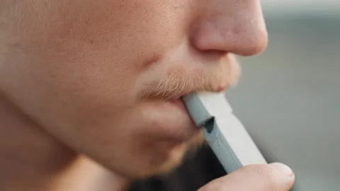 White male placing pod on lips, twilight rooftop rehearsal pause, musician Stock Footage 338004481