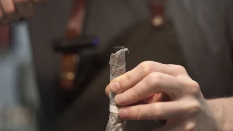 White male tanner in a workshop. Using a rubber mallet, he punches holes in Stock Footage 104925414