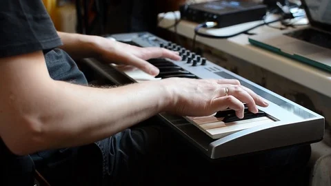 A white man in a black t-shirt plays his favorite tune on a synthesizer Stock Footage