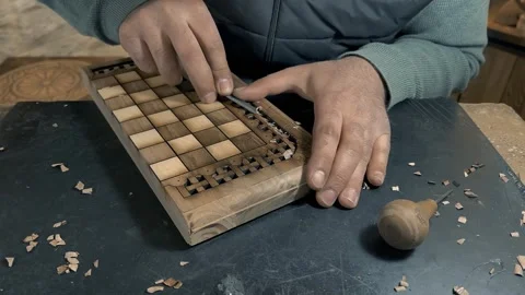 White man carves pattern on wooden chessboard with chisel. Male hand close up Stock Footage 274624583
