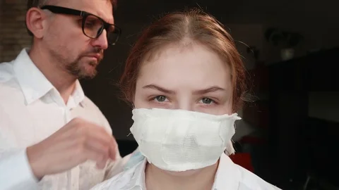 White man changes homemade face mask to factory medical mask on girl's face Stock Footage 125095043