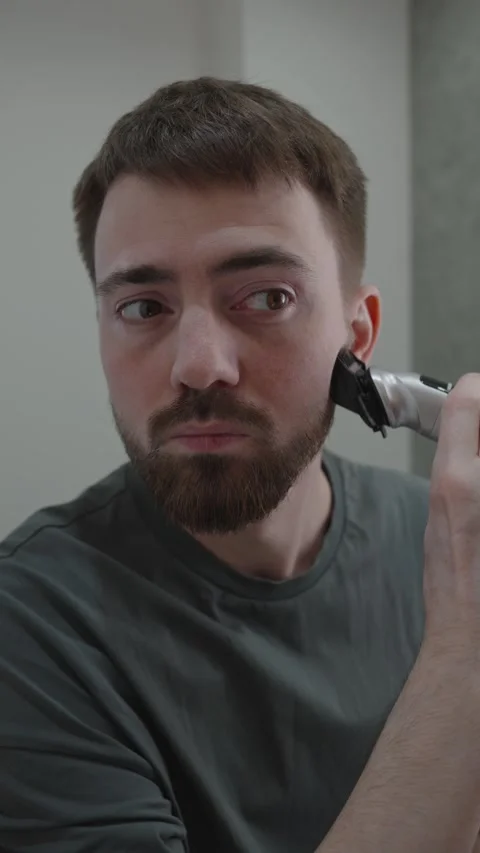 White man checking beard symmetry in mirror office interview prep Video stock 333332121