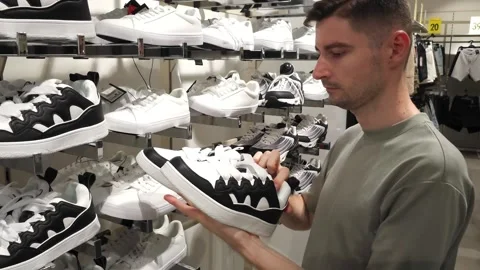 White man checking out black and white sneakers in a store. Stock Footage 283017026