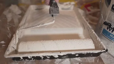 White man hand extending white paint on tray with painting roller handle Vidéo 148714074