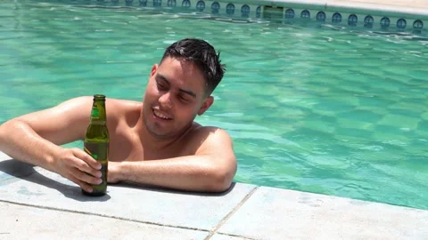 A white man having a beer in the pool with half body inside leaning his arms on Video stock 161962455