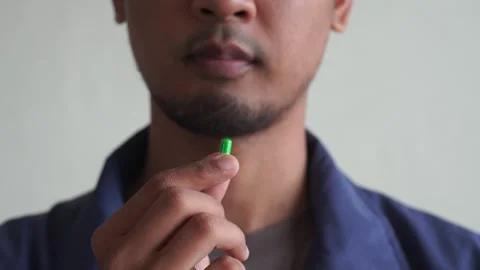 White man holding and taking green pill. Healthcare and medication concept. Stock Footage 328646448