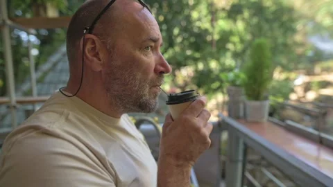 White Man Holding Coffee At Railing, Afternoon Glow, Urban Garden Backdrop Видео 329020363