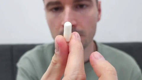 White man holding a white capsule pill between fingers Stock Footage 282610017