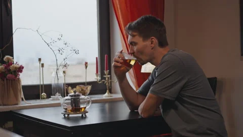 A white man at home drinking tea and looking out the window Stock Footage 294256397