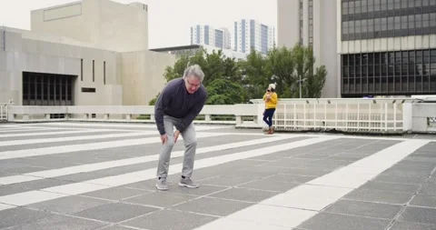 White man jogging on rooftop from knee pain then stretching walking while Stock Footage 337159677