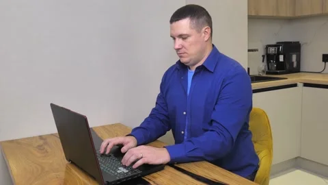White man in the kitchen working on a laptop. Work remotely at home Stock Footage 228284456