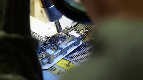 White man mounts new chip to motherboard of smartphone iphone in workshop Stock Footage 70875062
