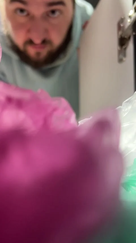 White man out of focus takes out multicolored plastic cellophane bag from closet Stock Footage 295245055