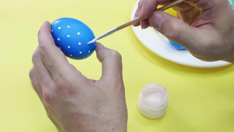 White man painting a blue Easter egg in polka dot with white acrylic color Stock Footage 172220520