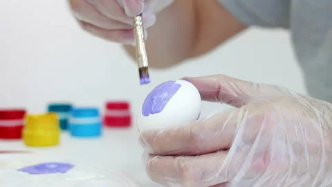 White man painting a purple Easter egg with a brush Stock Footage 172351602
