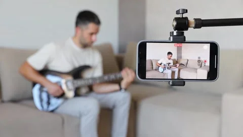 A white man play on electric guitar and records his playing on a smartphone. Stock Footage 276889161