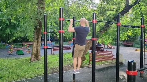 A white man pulls himself up on a horizontal bar Stock Footage 197356750