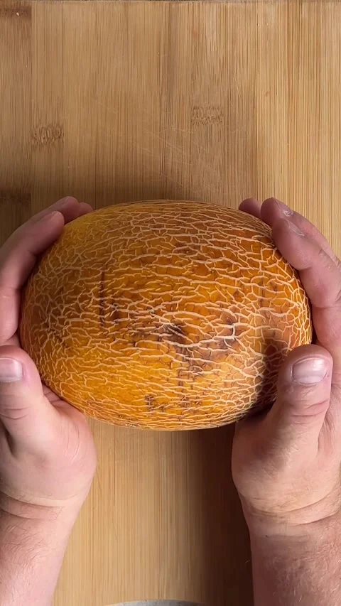 White man puts fresh raw yellow juicy delicious melon on wooden cutting board Stock Footage 280481790