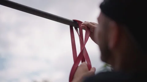 White Man Securing Red Band To Pullup Bar Overhead, Hands Tying Loop Around Stock Footage 324756403