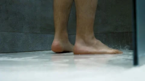 White man showering, ground-level close-up view on feet and water splashes. Vidéo 265619400