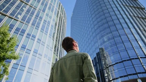 White man stand into camera focus a back view near an office building downtow Stock Footage 207041504
